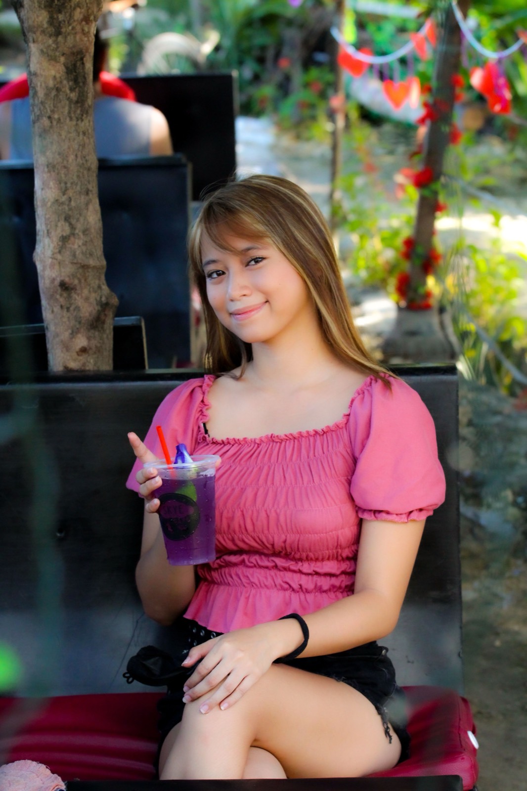 Illustrative photo of a Filipina woman smiling at an outdoor cafe