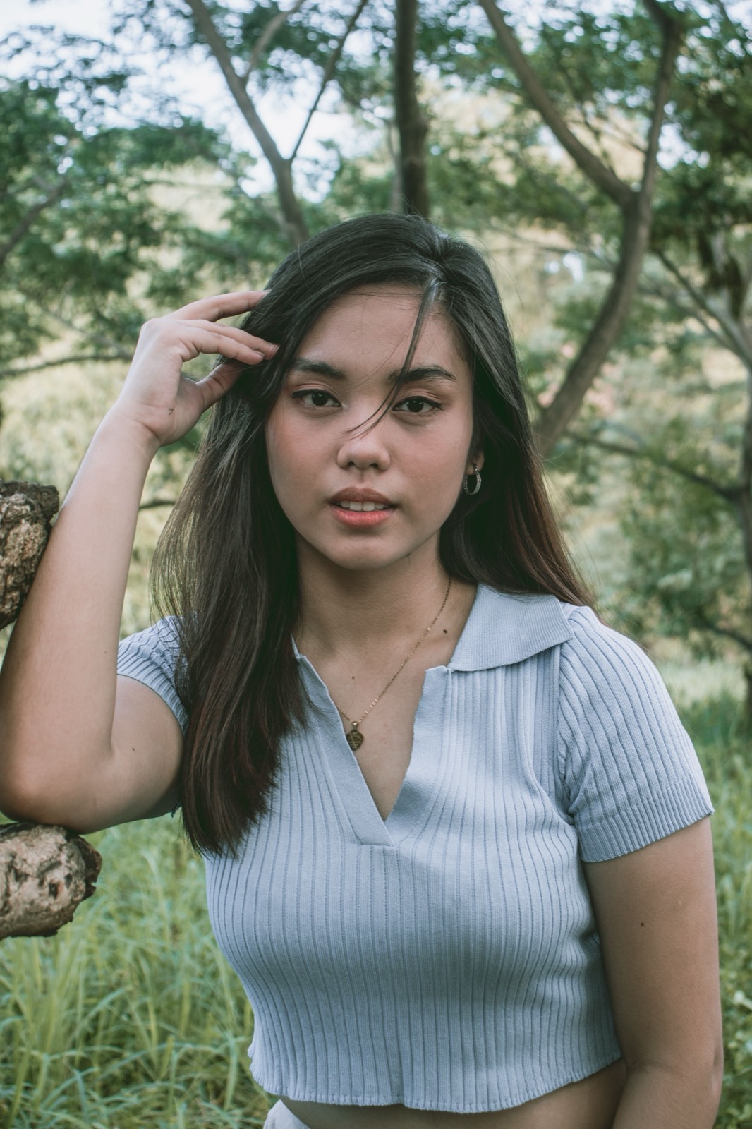 Illustrative stock photo of a Filipina woman in a light blue top outdoors