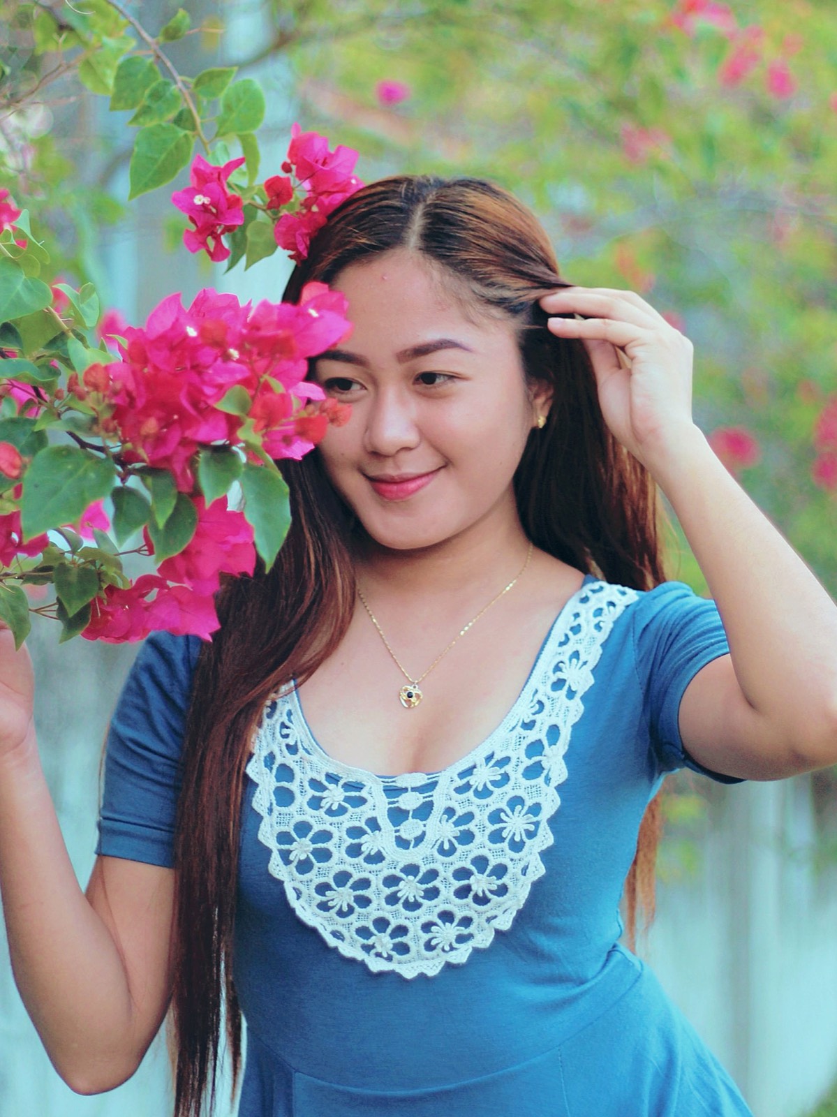 Illustrative stock photo of a Filipina woman beside bright pink bougainvillea