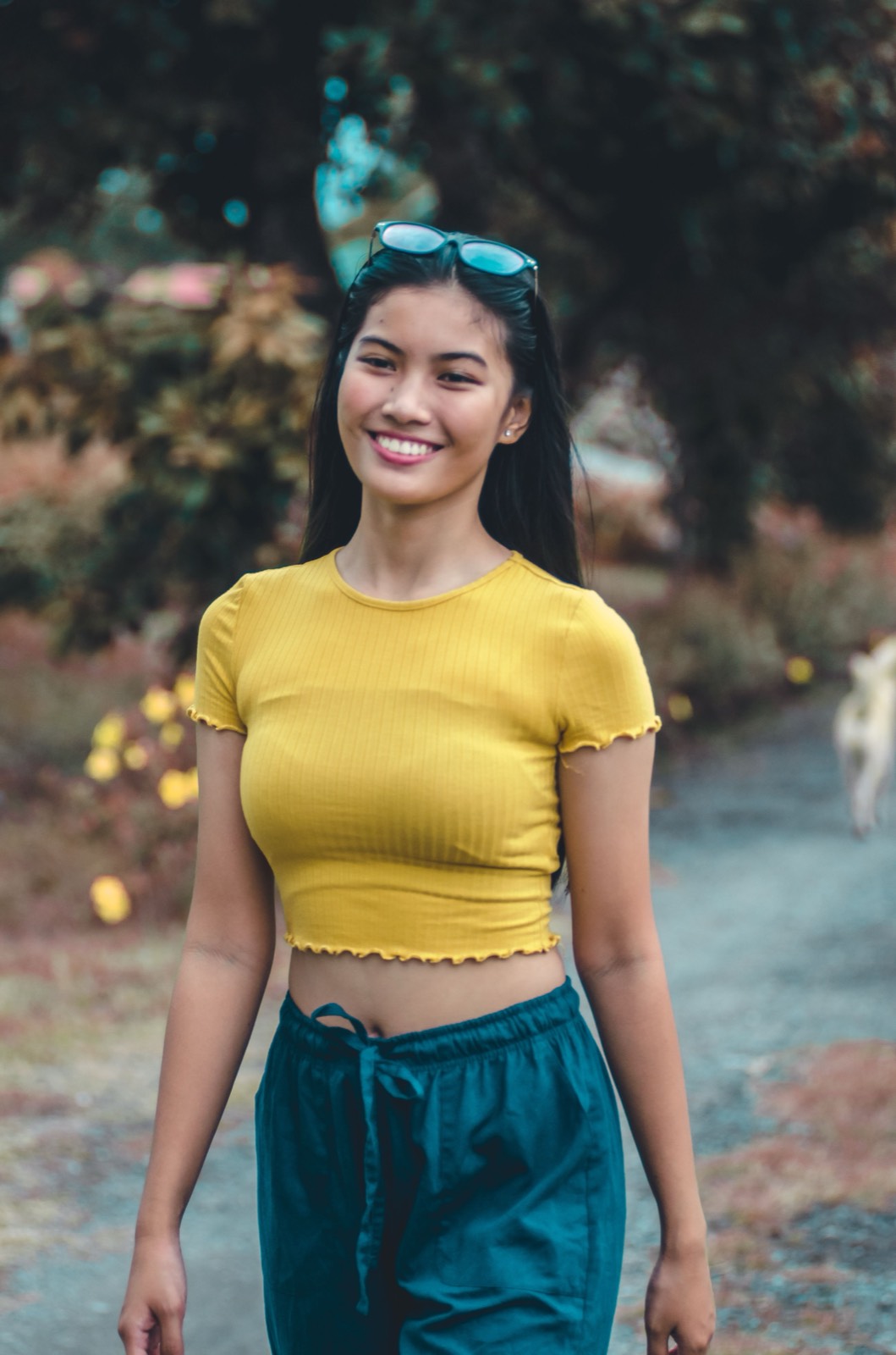 Illustrative stock photo of a smiling Filipina woman in a yellow top outdoors